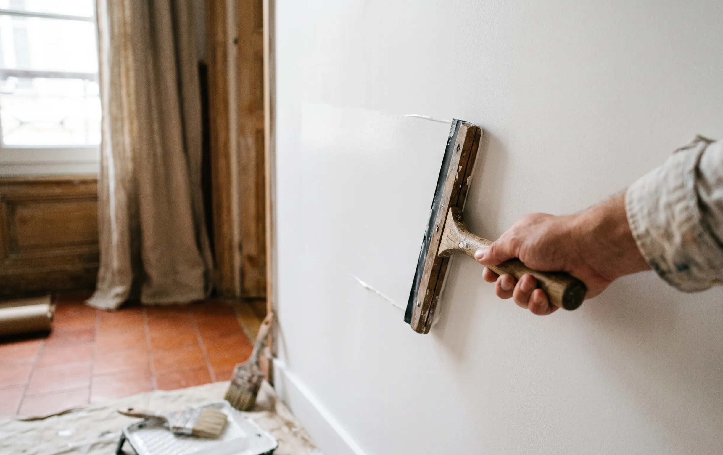 sticker sur mur : Gros plan sur une spatule de pose posée contre un mur blanc lisse avant le collage